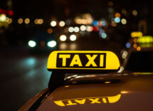 segno giallo e nero di taxi posto sopra un auto di notte